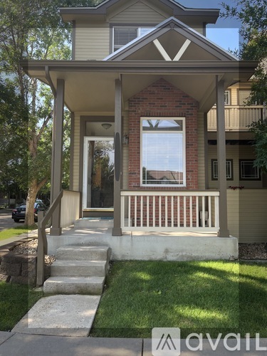 A house with a porch and a tree in front.