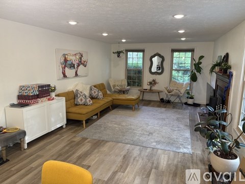 A living room with a yellow chair and a grey rug.