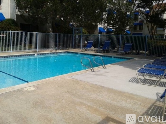 A pool surrounded by a metal fence and blue chairs.