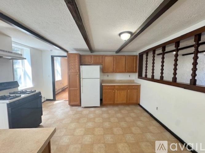 A kitchen with a white refrigerator, wooden cabinets, and a tiled floor.