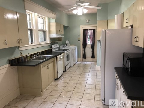 A kitchen with a black counter top and white appliances.