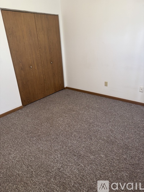 A room with a carpeted floor and a wooden door.