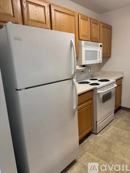 A white refrigerator is in a kitchen with wooden cabinets.