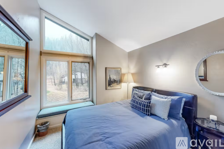 A bedroom with a large bed and a window overlooking a wooded area.