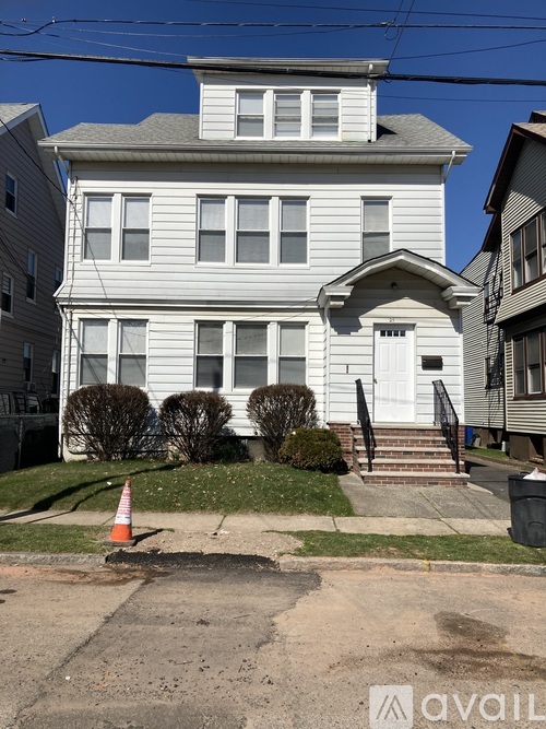 A white house with a grey roof and a black door.