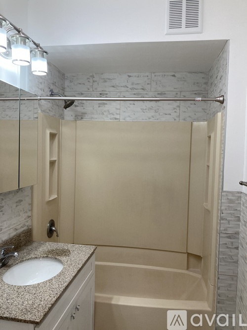 A bathroom with a sink, mirror, and shower.