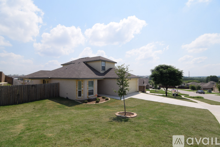 A house with a brown roof and a small tree in the front yard.