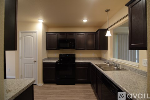 A kitchen with dark brown cabinets and a black microwave.