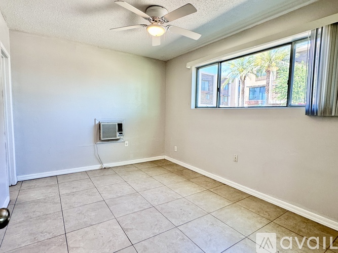 A room with a ceiling fan and a window overlooking a building.