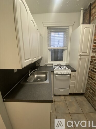A kitchen with white cabinets and a stove top oven.