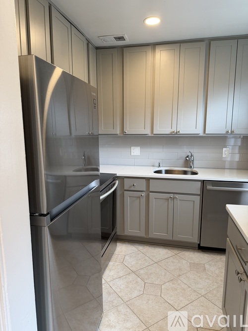 A kitchen with a stainless steel refrigerator and cabinets.