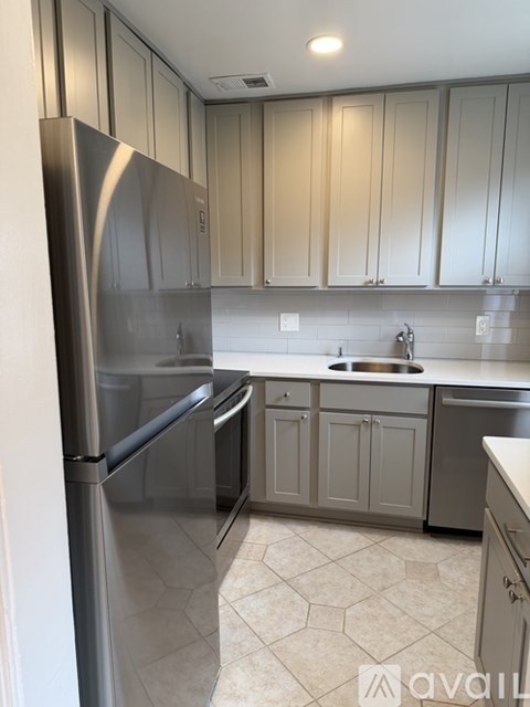 A kitchen with a stainless steel refrigerator and cabinets.