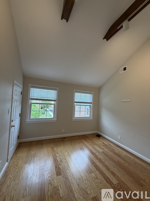 A room with wooden floors and two windows.