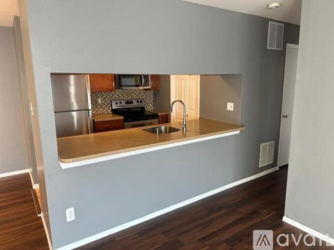 A kitchen with a stainless steel refrigerator and wooden flooring.