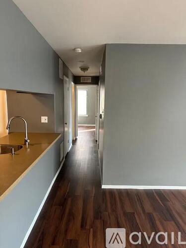 A long hallway with a sink on the left side and a door at the end.