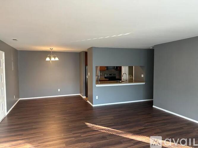 A spacious room with wooden floors and a large window.