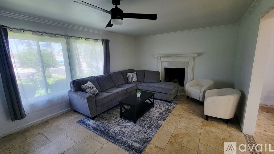 A living room with a grey couch, a black coffee table, and a white armchair.