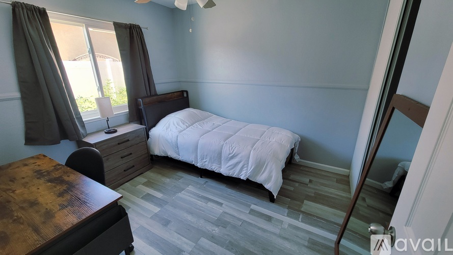 A bedroom with a bed, desk, and chair.