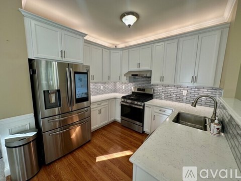 A kitchen with white cabinets and a stainless steel refrigerator.