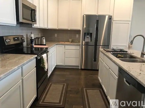 A kitchen with white cabinets and a stainless steel refrigerator.