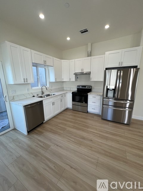 A kitchen with white cabinets and a wooden floor.