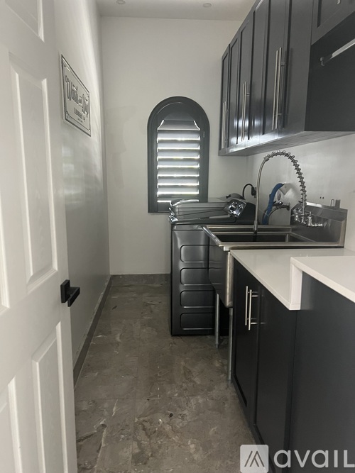 A kitchen with black cabinets and a white door.