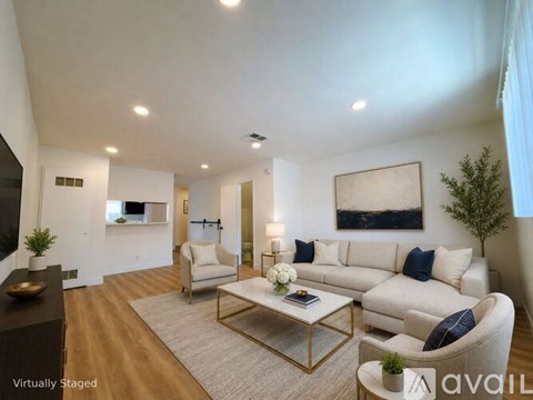 A living room with a white couch, a coffee table, and a painting on the wall.