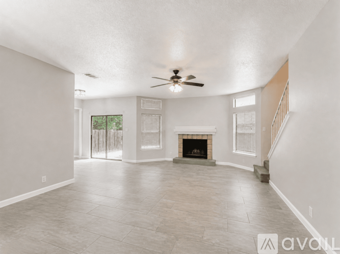 A spacious living room with a fireplace and a ceiling fan.