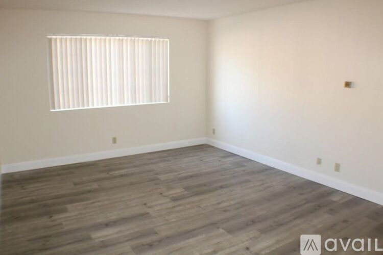 A room with wooden flooring and a window with blinds.