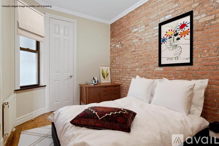 A bedroom with a white bed and a red and black pillow.