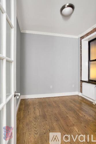 A room with wooden flooring and a window with a white frame.