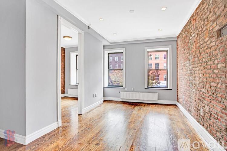 A spacious room with wooden floors and a brick wall on one side.