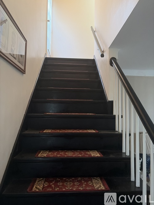 A staircase with a red runner and white balusters.