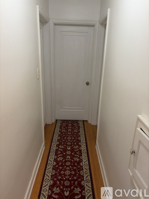 A hallway with a red and gold patterned carpet.
