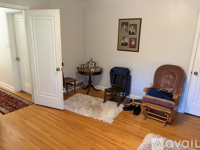 A living room with a chair, ottoman, and table.