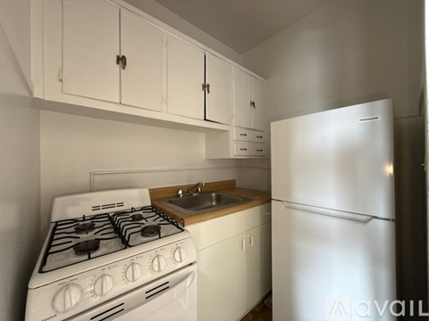 A white kitchen with a stove, sink, and cabinets.