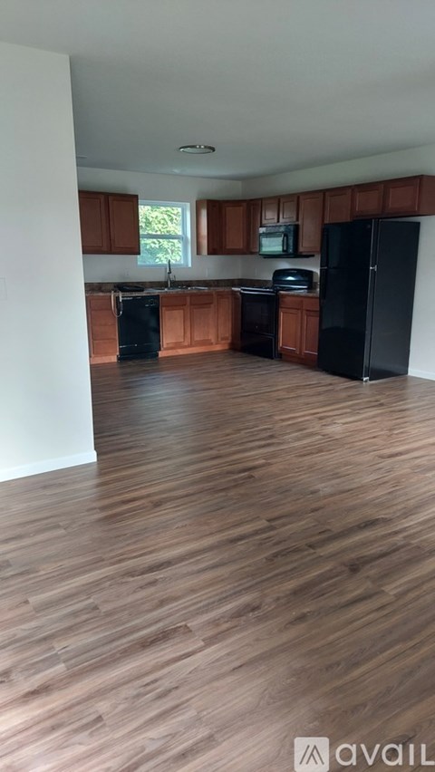 A kitchen with wooden floors and black appliances.