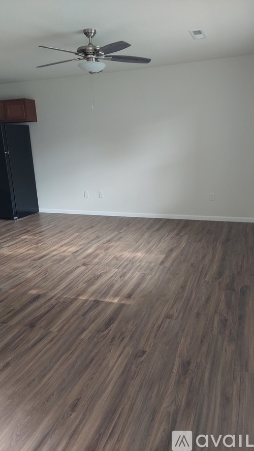 A room with a ceiling fan and wooden flooring.