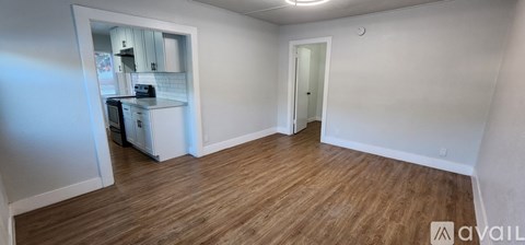 A small kitchen with white cabinets and a wooden floor.