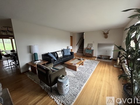A living room with a black couch and a grey rug.