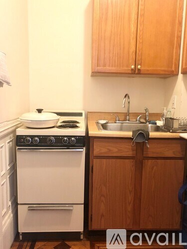 A white stove with a pot on it is in a kitchen with wooden cabinets.