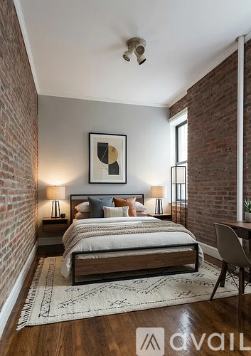 A bedroom with a bed, two lamps, a painting, and a rug.
