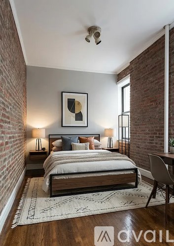 A bedroom with a bed, two lamps, a painting, and a rug.