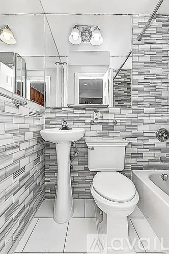 A bathroom with a white toilet, sink, and a stone wall.