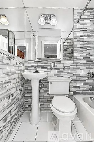 A bathroom with a white toilet, sink, and a stone wall.