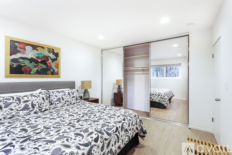 A bedroom with a large bed and a painting on the wall.
