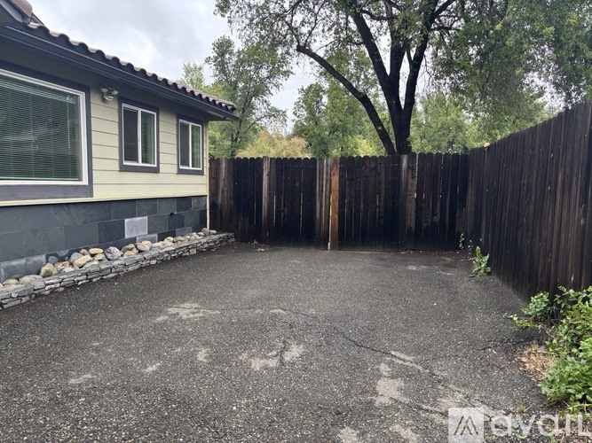 A backyard with a wooden fence and a grey house.