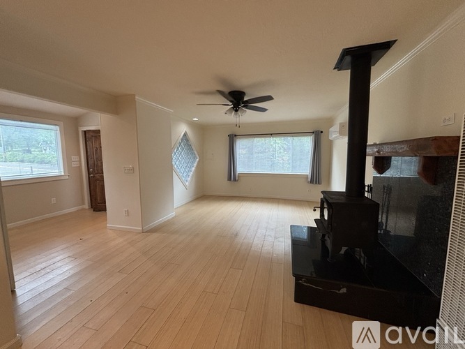 A living room with a wood burning stove and a ceiling fan.