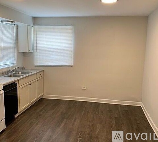 A kitchen with white cabinets and a wooden floor.