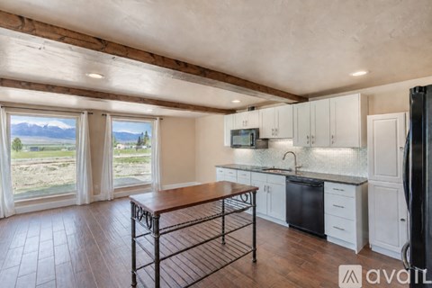 A kitchen with white cabinets and a black fridge.